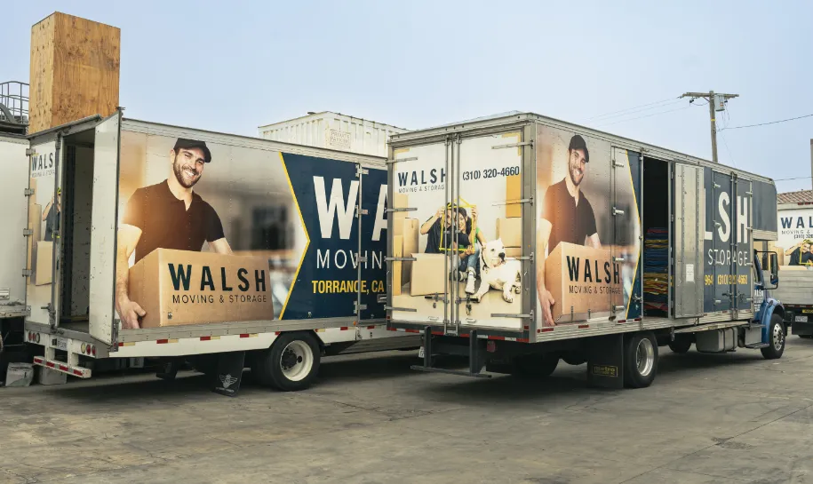 Two Walsh Moving & Storage trucks are parked side by side.