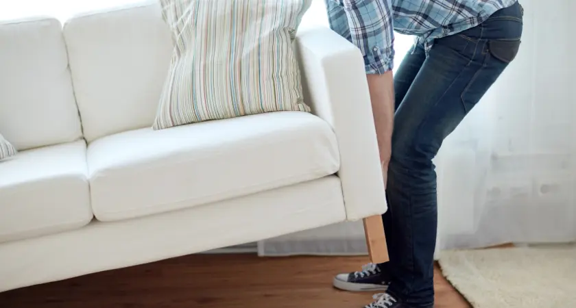 A man moving a couch by himself